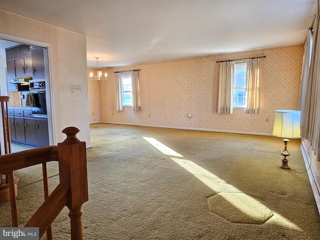 unfurnished living room featuring carpet and an inviting chandelier