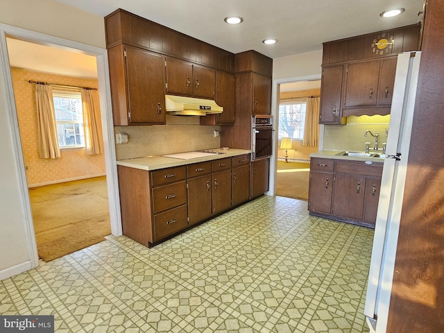 kitchen featuring stovetop, black oven, a healthy amount of sunlight, and sink