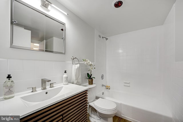 full bathroom featuring tasteful backsplash, vanity, tiled shower / bath combo, tile walls, and toilet