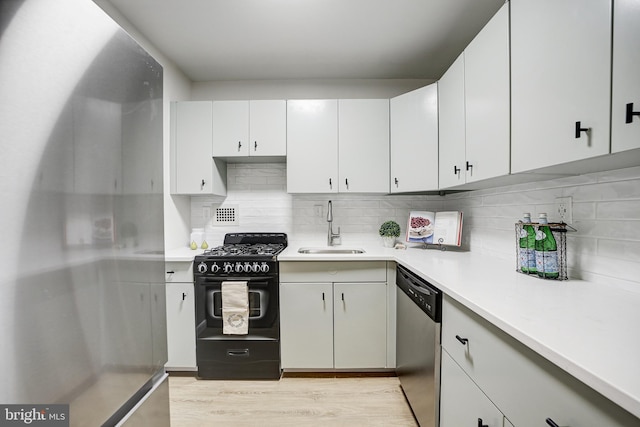 kitchen featuring backsplash, stainless steel dishwasher, black gas range oven, sink, and white cabinets