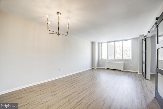 interior space featuring a barn door, a chandelier, light wood-type flooring, and radiator