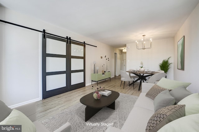 living room with a barn door, light hardwood / wood-style floors, and a notable chandelier