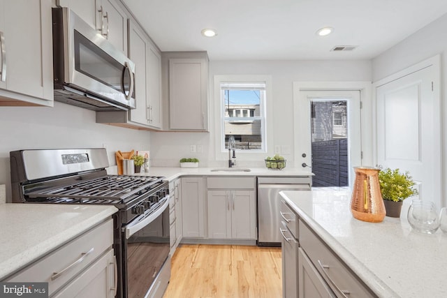 kitchen featuring appliances with stainless steel finishes, sink, gray cabinetry, and light hardwood / wood-style flooring