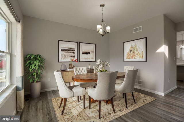 dining space featuring dark wood-type flooring and a chandelier