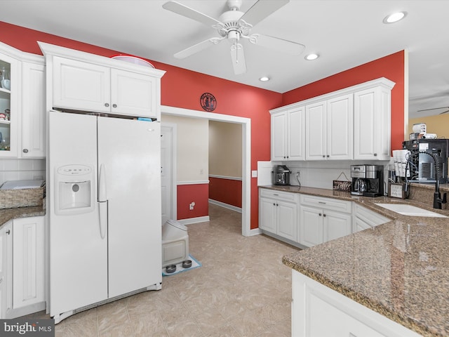 kitchen with ceiling fan, white refrigerator with ice dispenser, and white cabinets