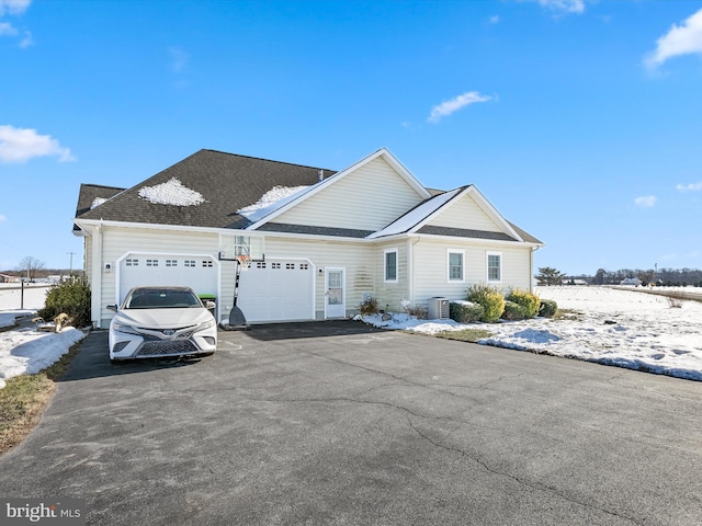 view of front of house with a garage, aphalt driveway, and cooling unit