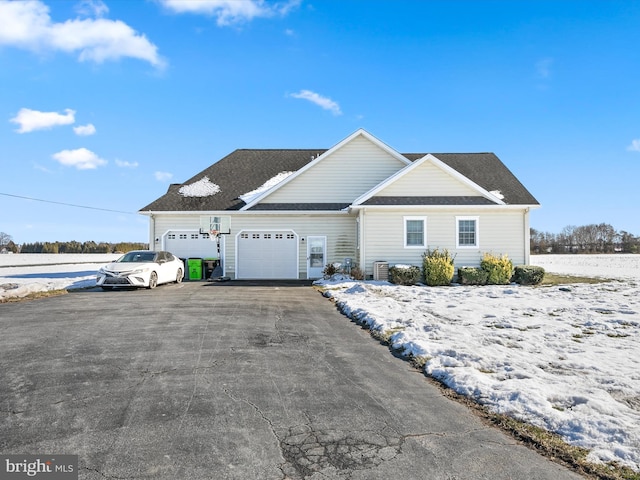 view of front of house featuring a garage, cooling unit, and driveway