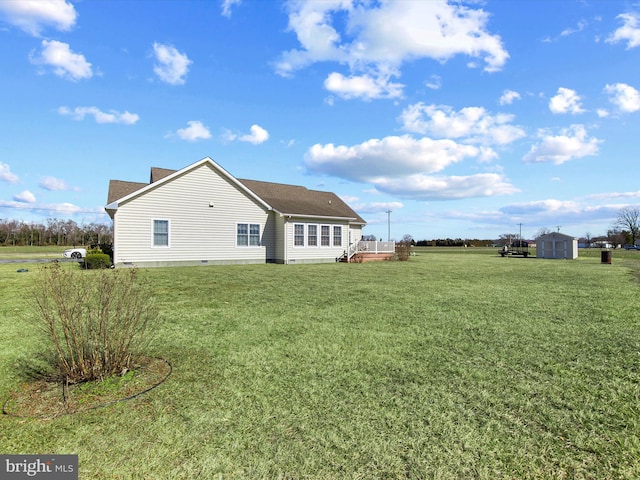 rear view of property with crawl space, a yard, a shed, and an outdoor structure