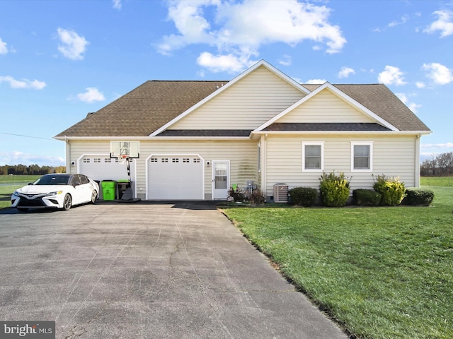 view of front of house with driveway, a garage, roof with shingles, central AC, and a front yard