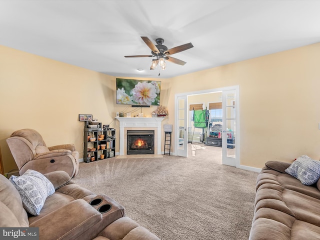 living room with carpet floors, french doors, a fireplace with flush hearth, ceiling fan, and baseboards