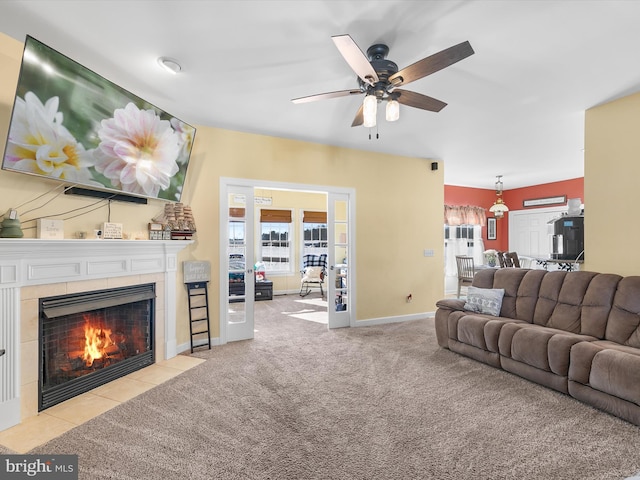 living area featuring ceiling fan, a fireplace, baseboards, and carpet flooring