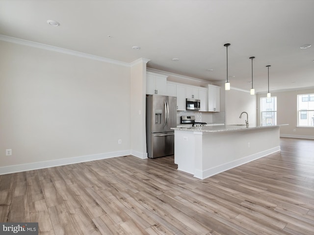 kitchen with stainless steel appliances, white cabinetry, hanging light fixtures, a kitchen island with sink, and crown molding