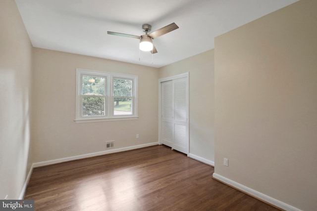 unfurnished bedroom featuring dark hardwood / wood-style flooring, ceiling fan, and a closet