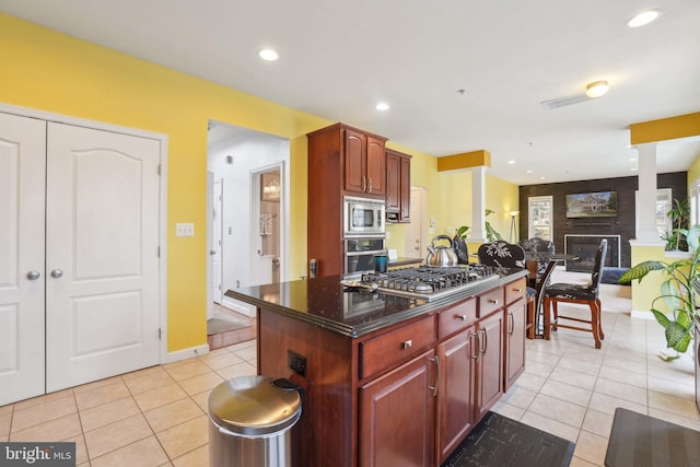 kitchen with stainless steel appliances, a center island, light tile patterned floors, and a fireplace