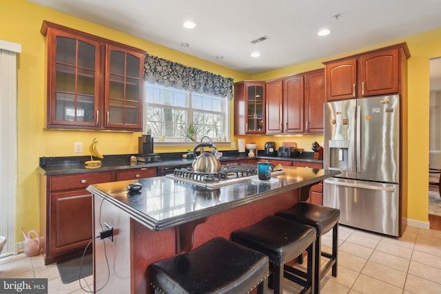 kitchen featuring appliances with stainless steel finishes, a center island, a breakfast bar area, and light tile patterned floors