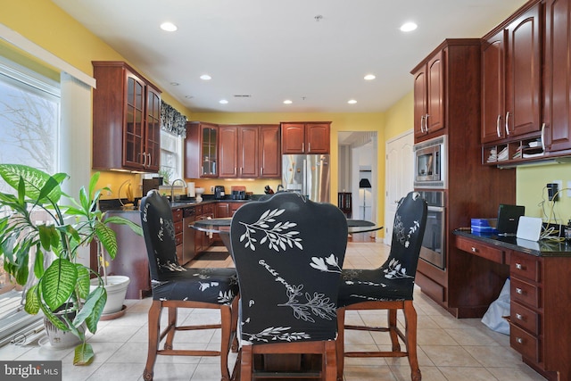 kitchen with light tile patterned floors, built in desk, stainless steel appliances, and sink