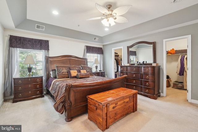 carpeted bedroom featuring a tray ceiling, a spacious closet, a closet, and ceiling fan