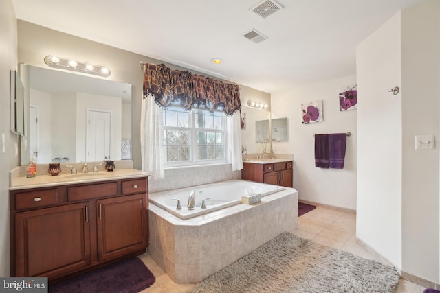 bathroom featuring tile patterned flooring, vanity, and tiled bath