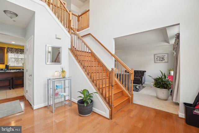 stairway with wood-type flooring and a high ceiling