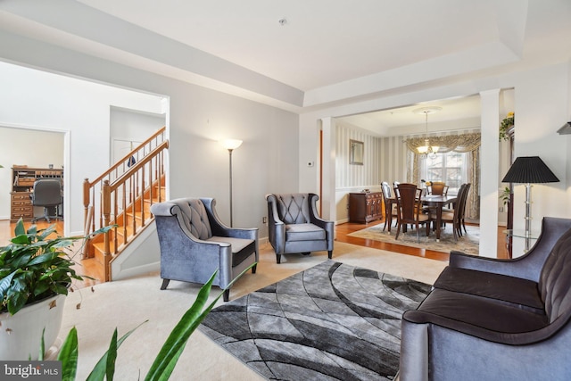 living room featuring a notable chandelier, a tray ceiling, and light colored carpet