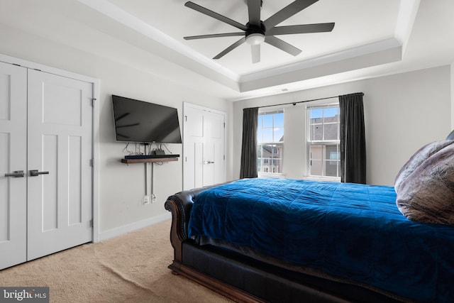 carpeted bedroom featuring a raised ceiling and ceiling fan