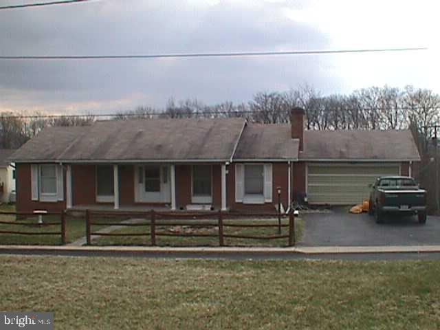 ranch-style house with a front yard, a porch, and a garage