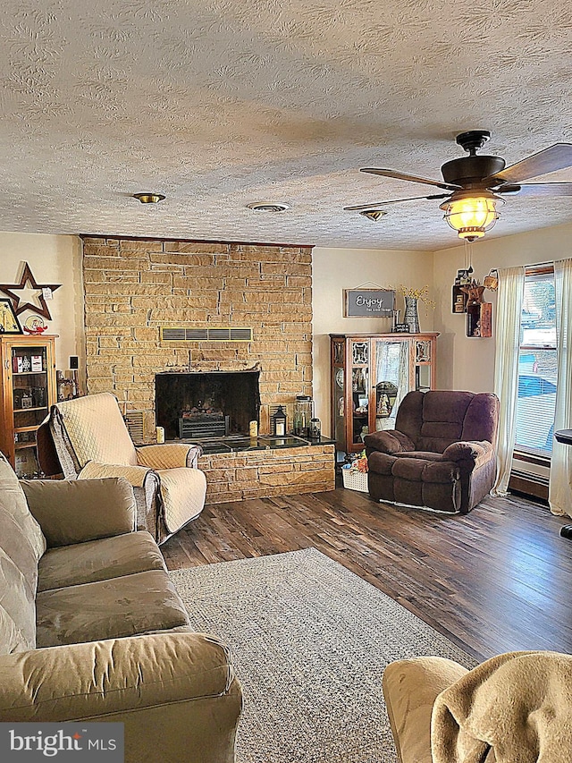 living room with hardwood / wood-style floors, ceiling fan, a fireplace, and a textured ceiling