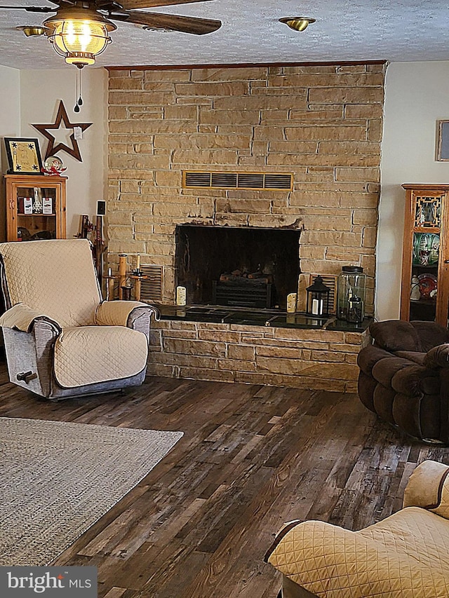 living room with hardwood / wood-style flooring, a fireplace, ceiling fan, and a textured ceiling