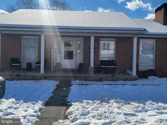 snow covered property entrance with covered porch