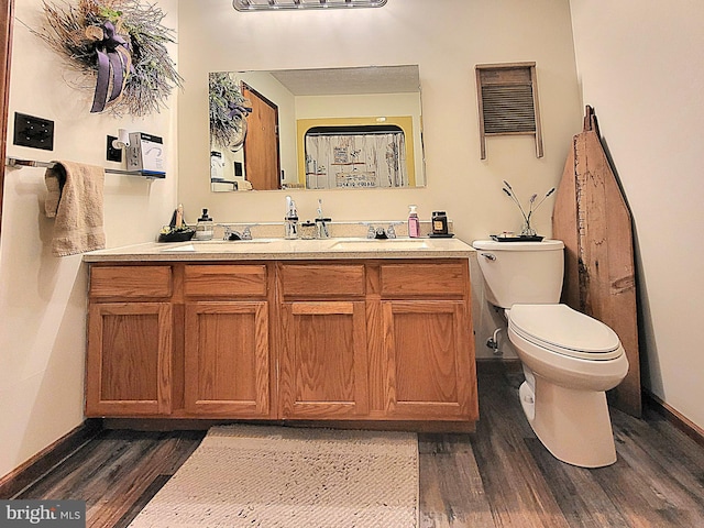 bathroom with hardwood / wood-style floors, vanity, and toilet