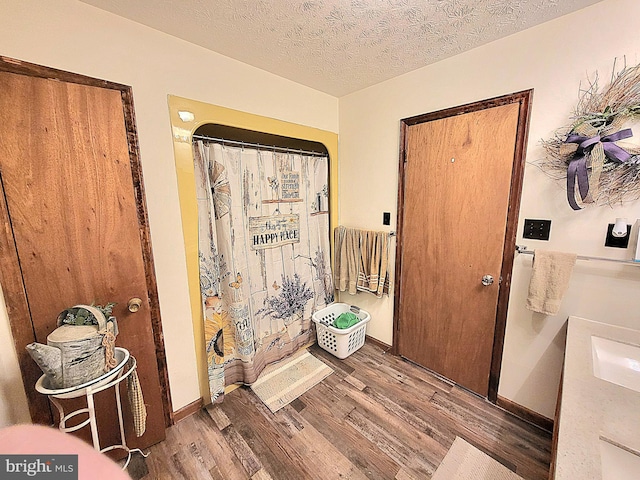 bathroom with hardwood / wood-style floors, curtained shower, sink, and a textured ceiling