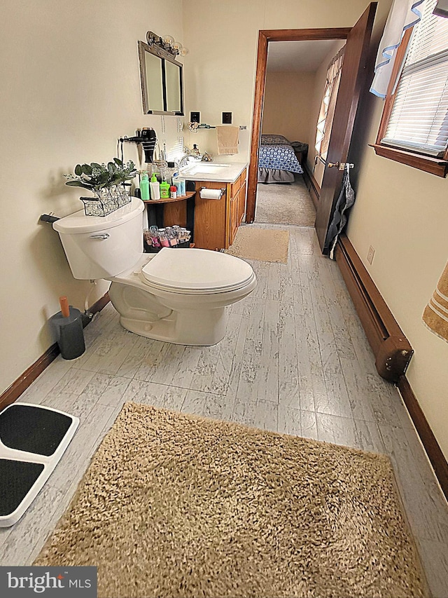 bathroom with vanity, toilet, wood-type flooring, and baseboard heating