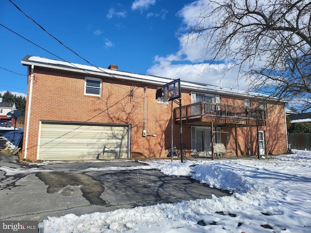 snow covered property featuring a garage, a deck, and a balcony