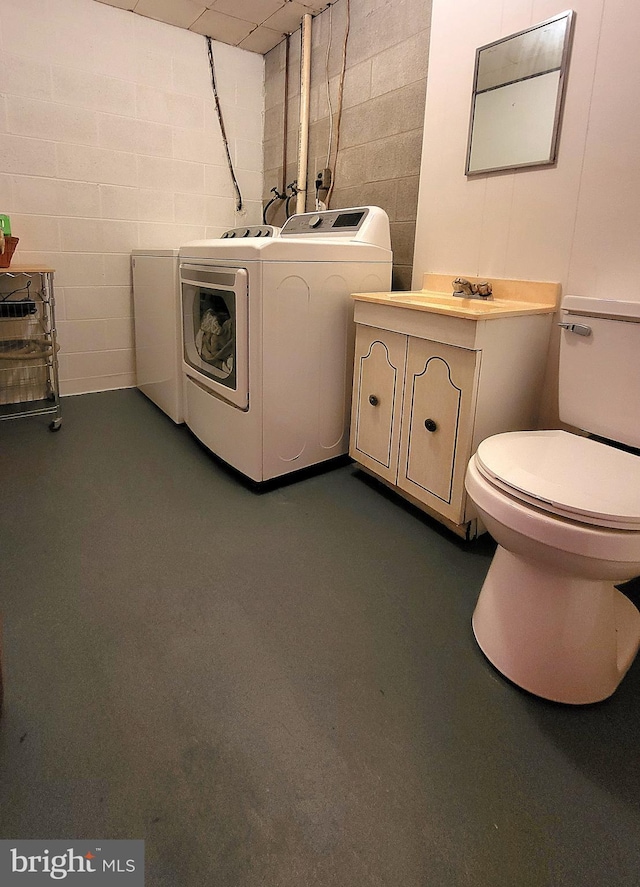 interior space featuring concrete flooring, vanity, washing machine and dryer, and toilet