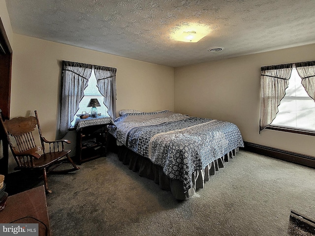 carpeted bedroom with baseboard heating and a textured ceiling