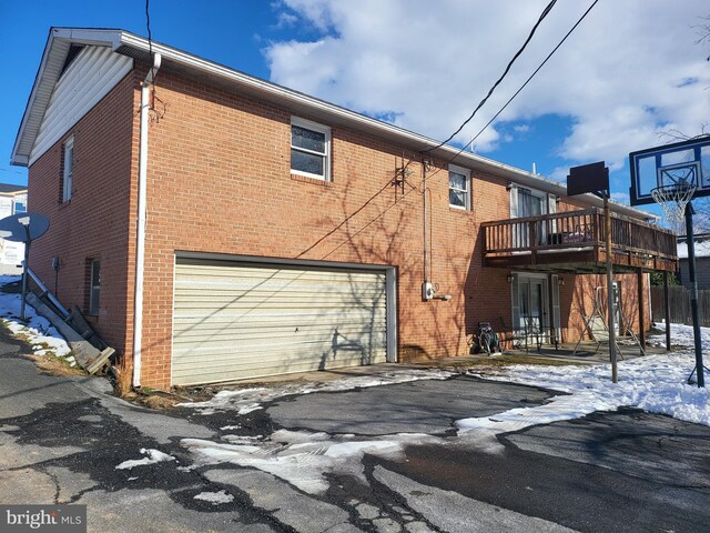 snow covered rear of property with a balcony and a garage