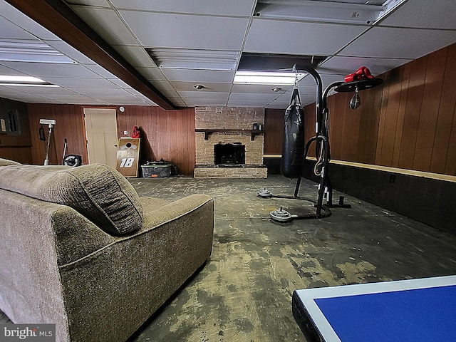 interior space featuring a fireplace, a drop ceiling, and wooden walls