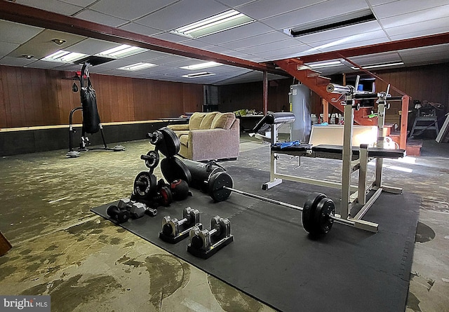 gym with a paneled ceiling and wood walls