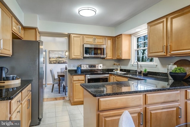 kitchen featuring appliances with stainless steel finishes, sink, dark stone counters, and kitchen peninsula