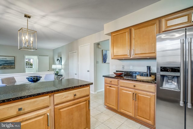 kitchen featuring pendant lighting, stainless steel fridge, light tile patterned floors, and dark stone countertops