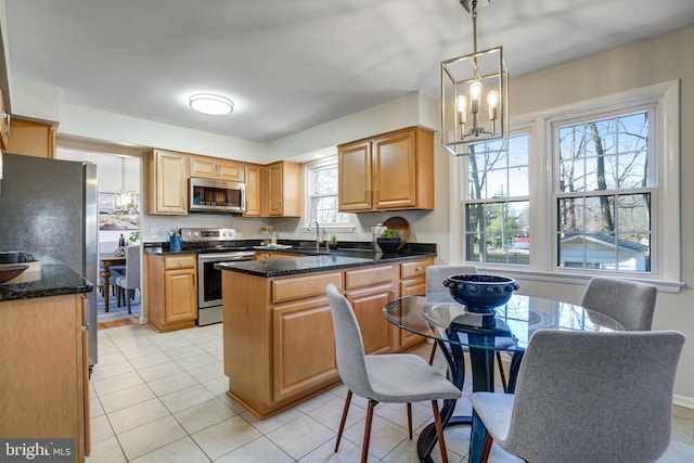 kitchen with a kitchen island, pendant lighting, sink, dark stone counters, and stainless steel appliances