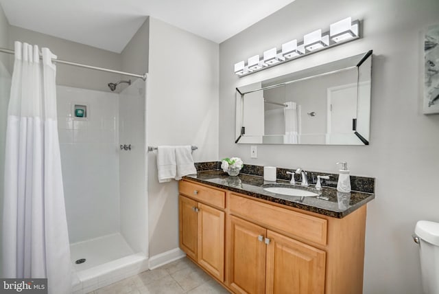 bathroom with tile patterned flooring, vanity, toilet, and walk in shower