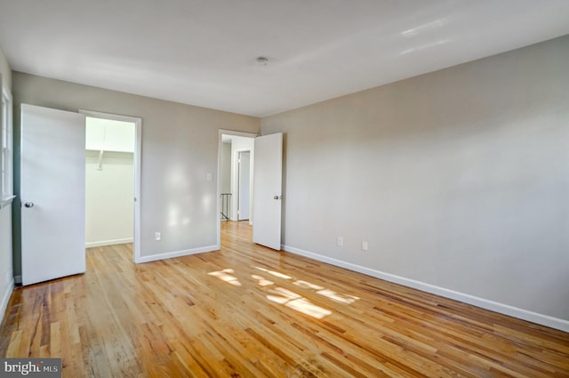 unfurnished bedroom with a spacious closet, light hardwood / wood-style floors, and a closet