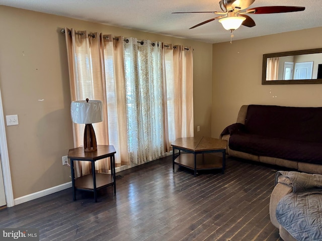 living room with dark wood-type flooring, ceiling fan, and a textured ceiling