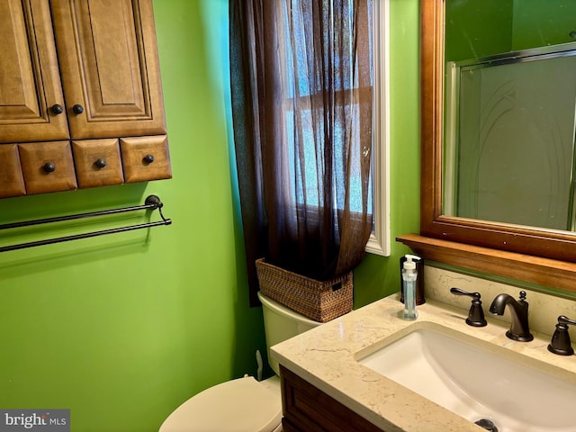 bathroom with vanity, toilet, and a shower with shower door