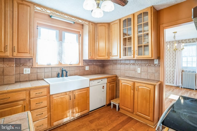 kitchen featuring dishwasher, radiator, hanging light fixtures, sink, and tile counters