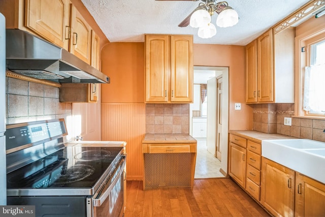 kitchen featuring stainless steel range with electric stovetop, sink, ceiling fan, a textured ceiling, and light hardwood / wood-style floors