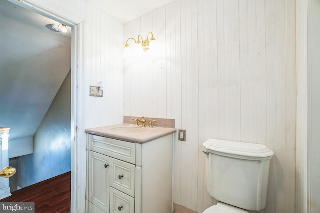 bathroom featuring vanity, toilet, wood-type flooring, and wooden walls