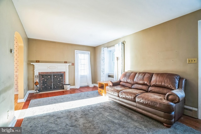 living room featuring a fireplace, light wood-type flooring, and a baseboard heating unit