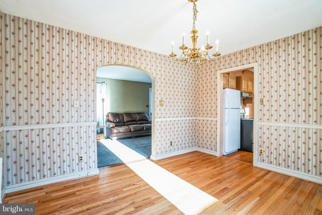 unfurnished dining area with a notable chandelier and wood-type flooring